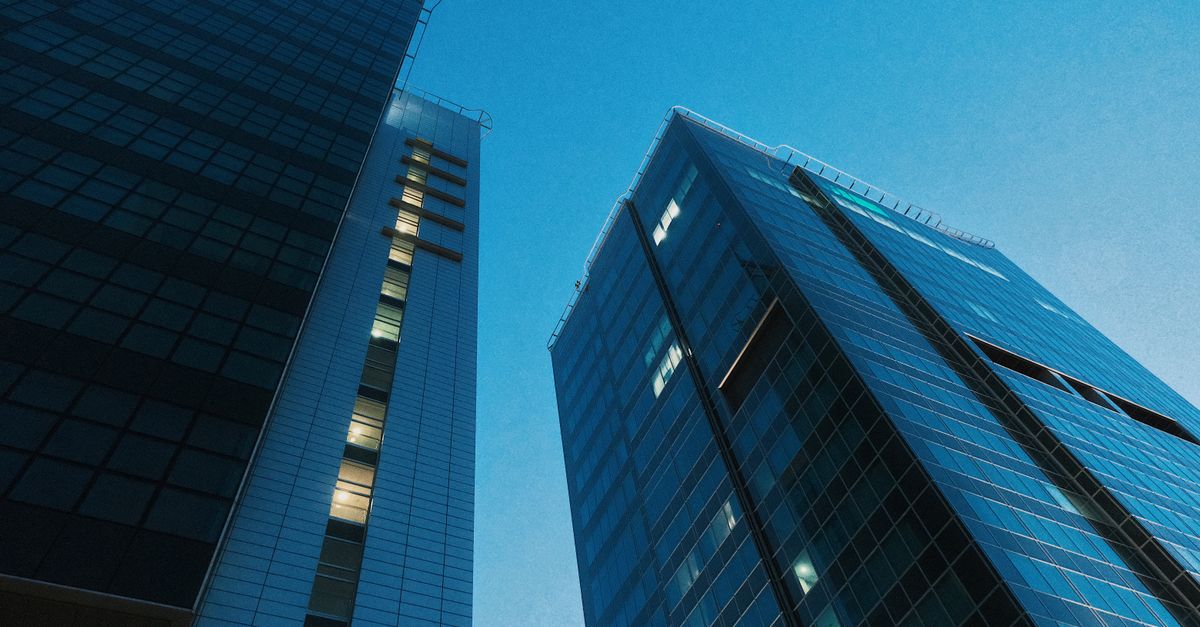 Low angle view of modern skyscrapers with glass facades against a clear evening sky in Poznań, Poland.